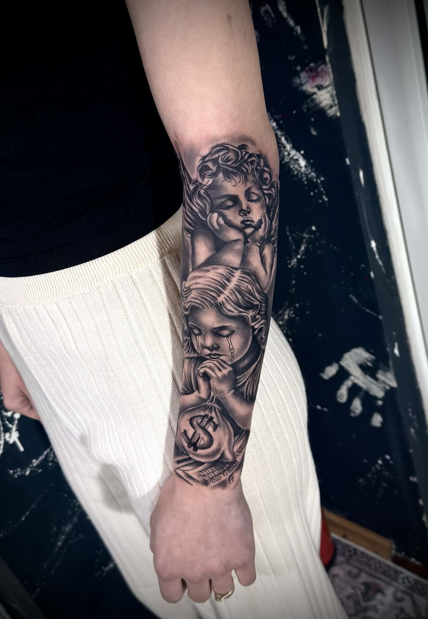 Tatuaj alb-negru cu, copii si bani pe braț - AlexuU Tattoo Craiova